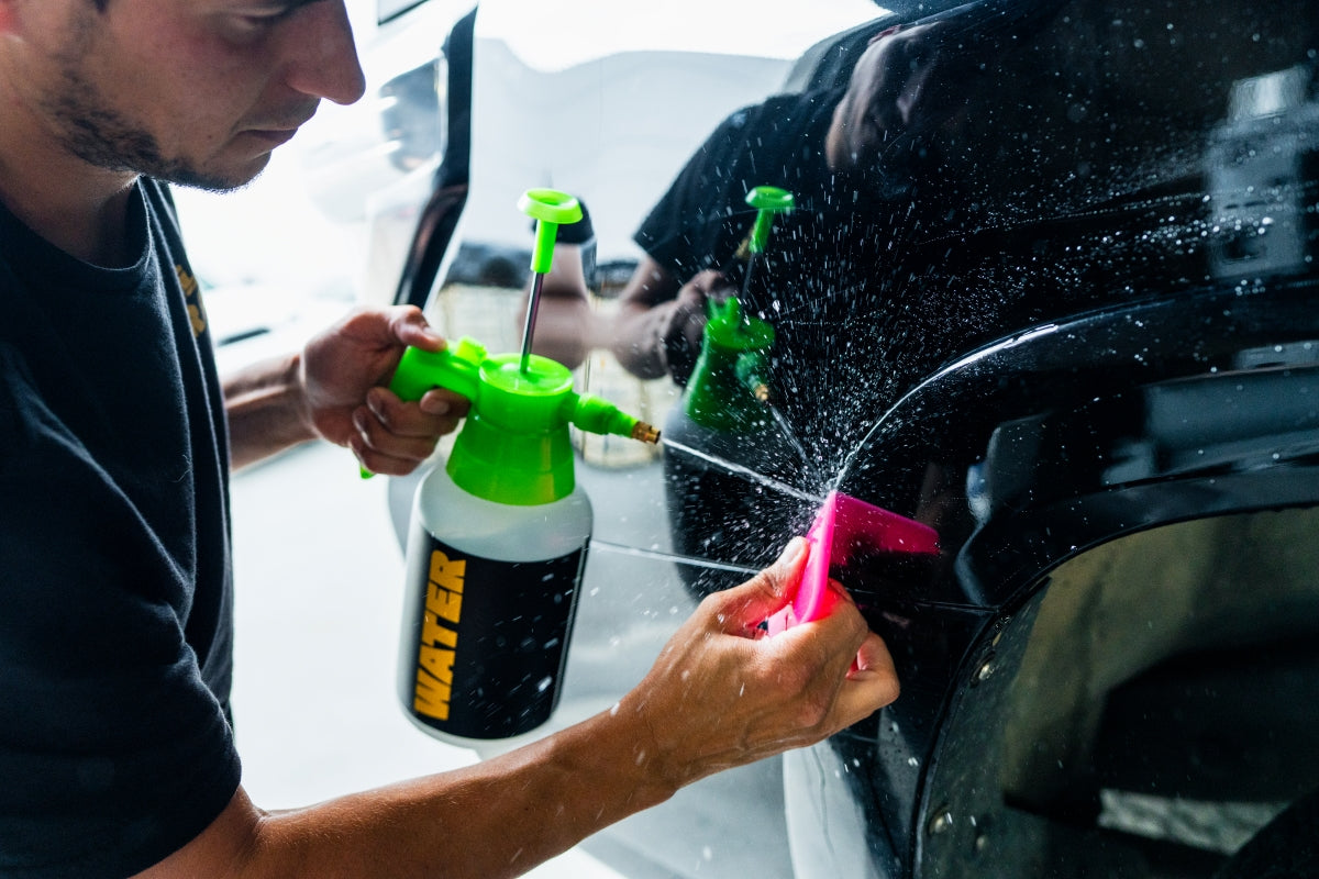 Squeegeeing paint protection film while spraying water along the edge during WildWrap DIY installation