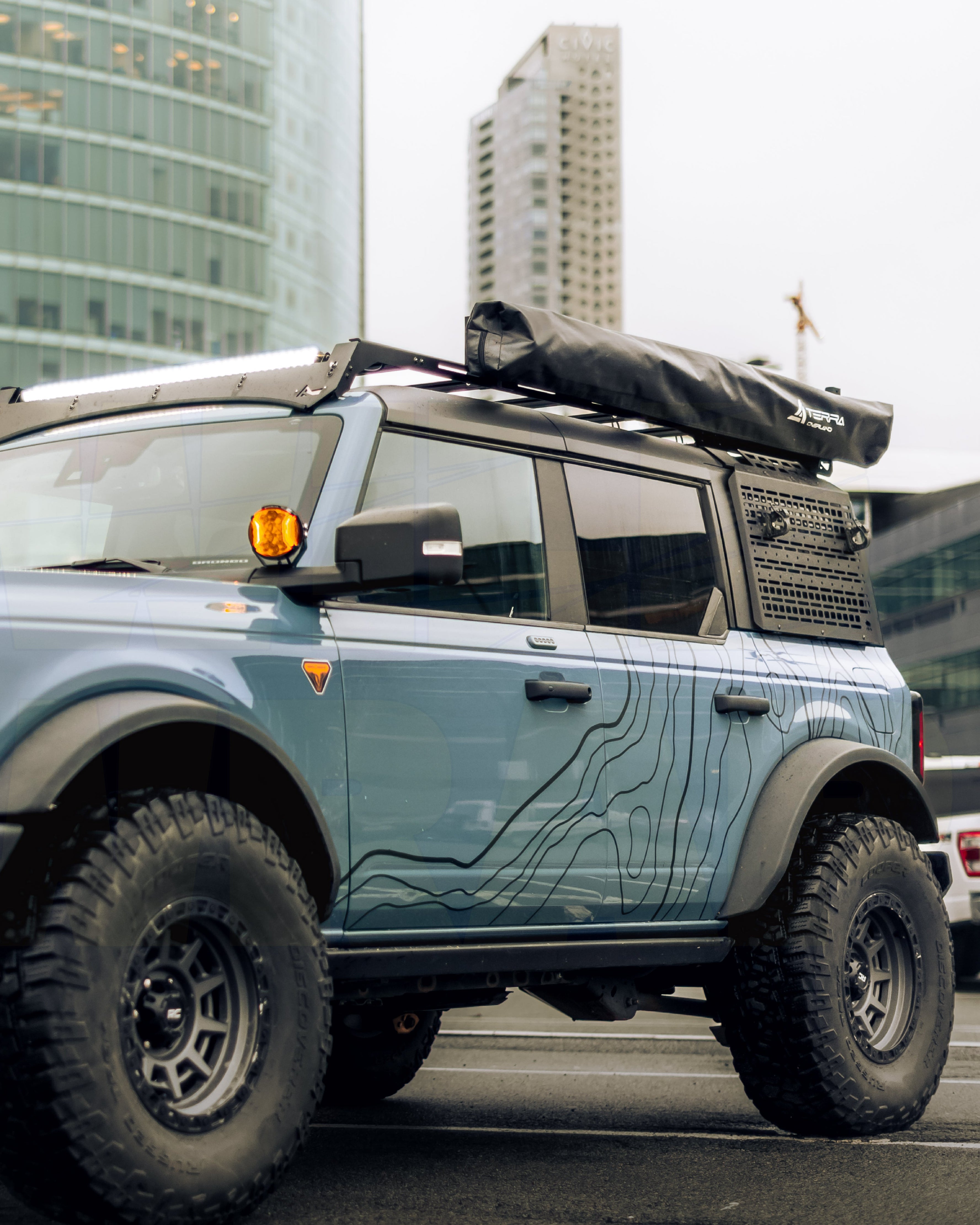 Topographic vinyl decals installed on a vehicle bronco doors with contour lines and peak markers