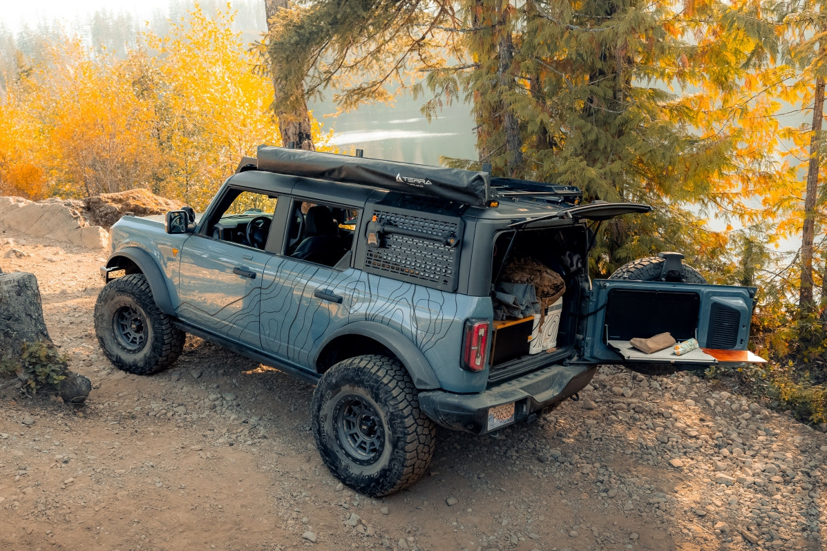 Overland bronco camp scene showing a truck with topographic vinyl decals and topo lines